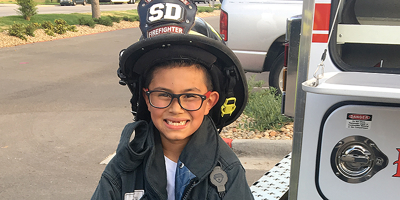 kid in firefighter helmet smiling